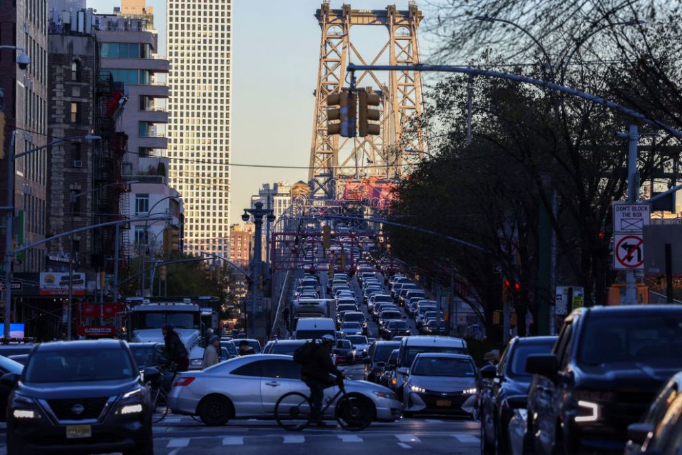 Pedestrians, cyclists and cars move along Delancey Street, with the Williamsburg Bridge in the background, in the Manhattan borough of New York on November 13, 2024. New York Governor Kathy Hochul is expected to make an announcement on November 14, regarding congestion pricing in New York City, according to her office. Hochul had previously expressed her intention to lift the pause on the plan and lower the toll from $15 to $9.