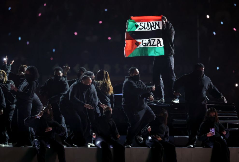 NEW ORLEANS, LOUISIANA - FEBRUARY 09: A protester holds a flag onstage during Apple Music Super Bowl LIX Halftime Show at Caesars Superdome on February 09, 2025 in New Orleans, Louisiana.